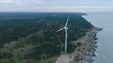 establishing aerial view of abandoned seaside fortification buildings at karosta northern forts on the beach of baltic sea in liepaja, overcast day, wind turbine, drone shot moving forward