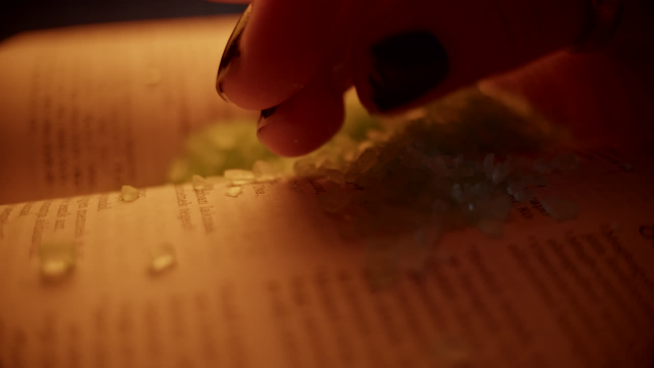 Hand Sprinkling Bath Salt on Open Book