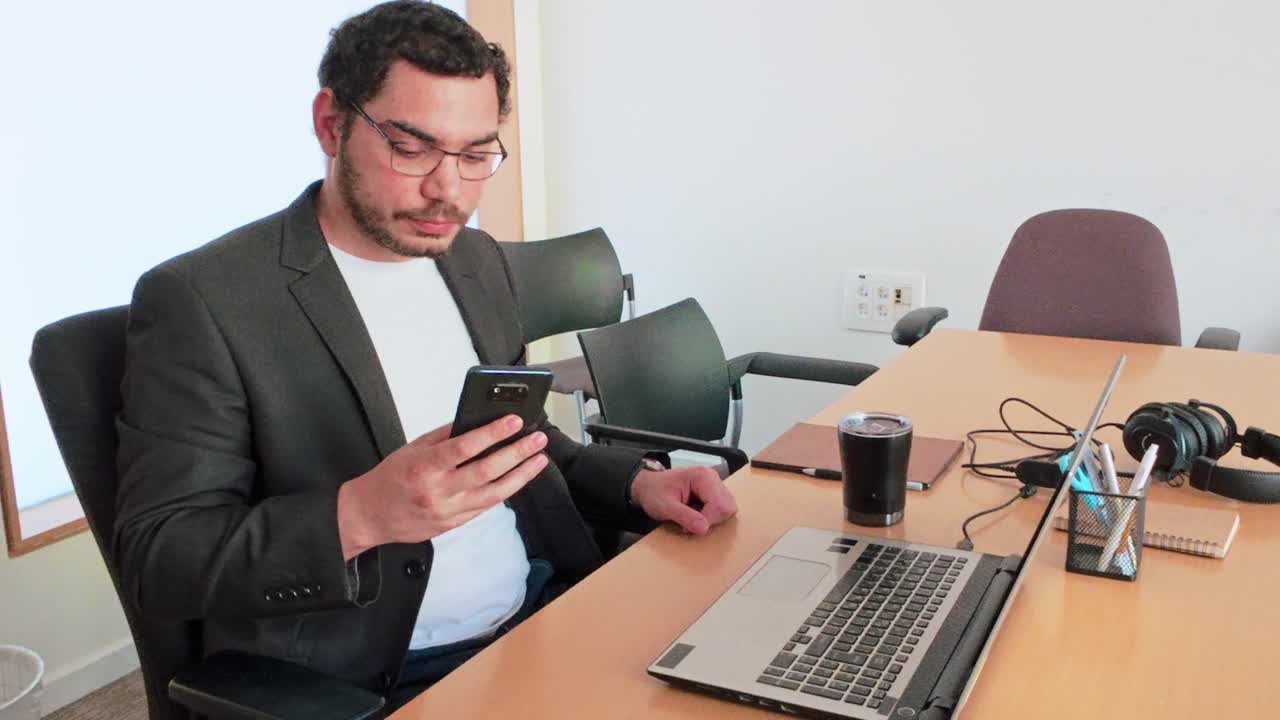 A man is talking on his cell phone while sitting at a desk