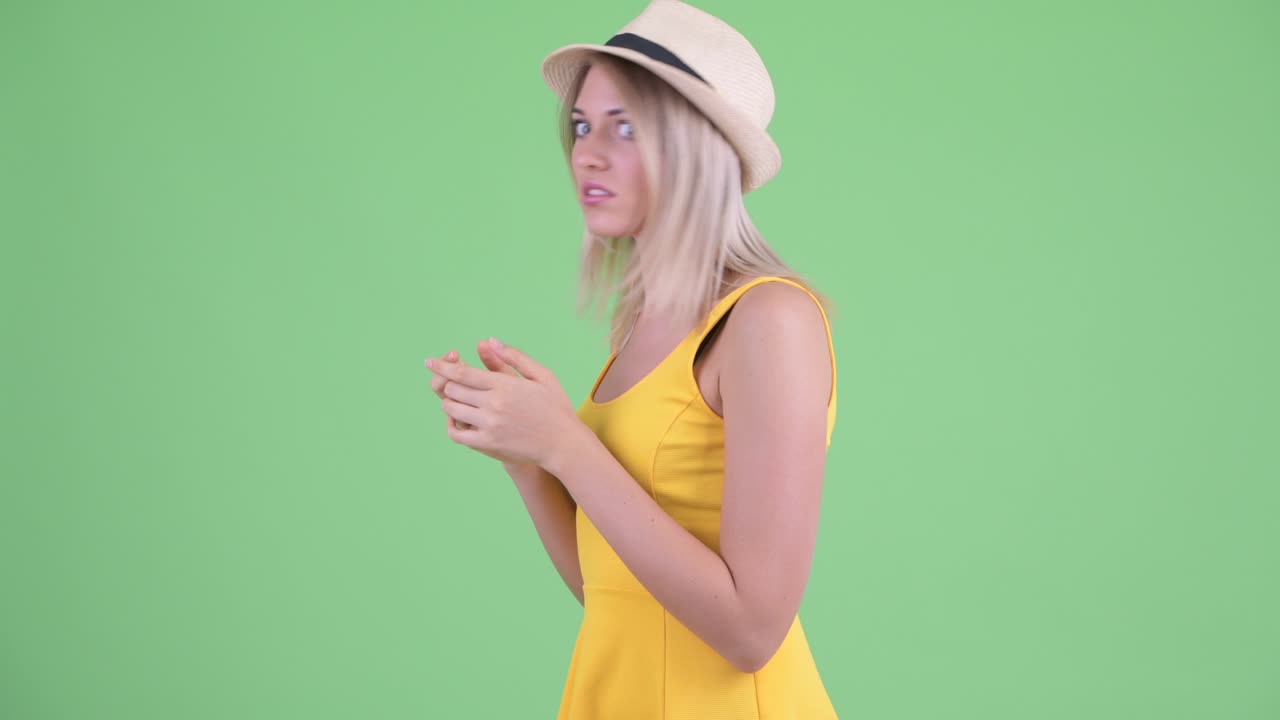Studio shot of young tourist woman using phone while someone steal it against green background