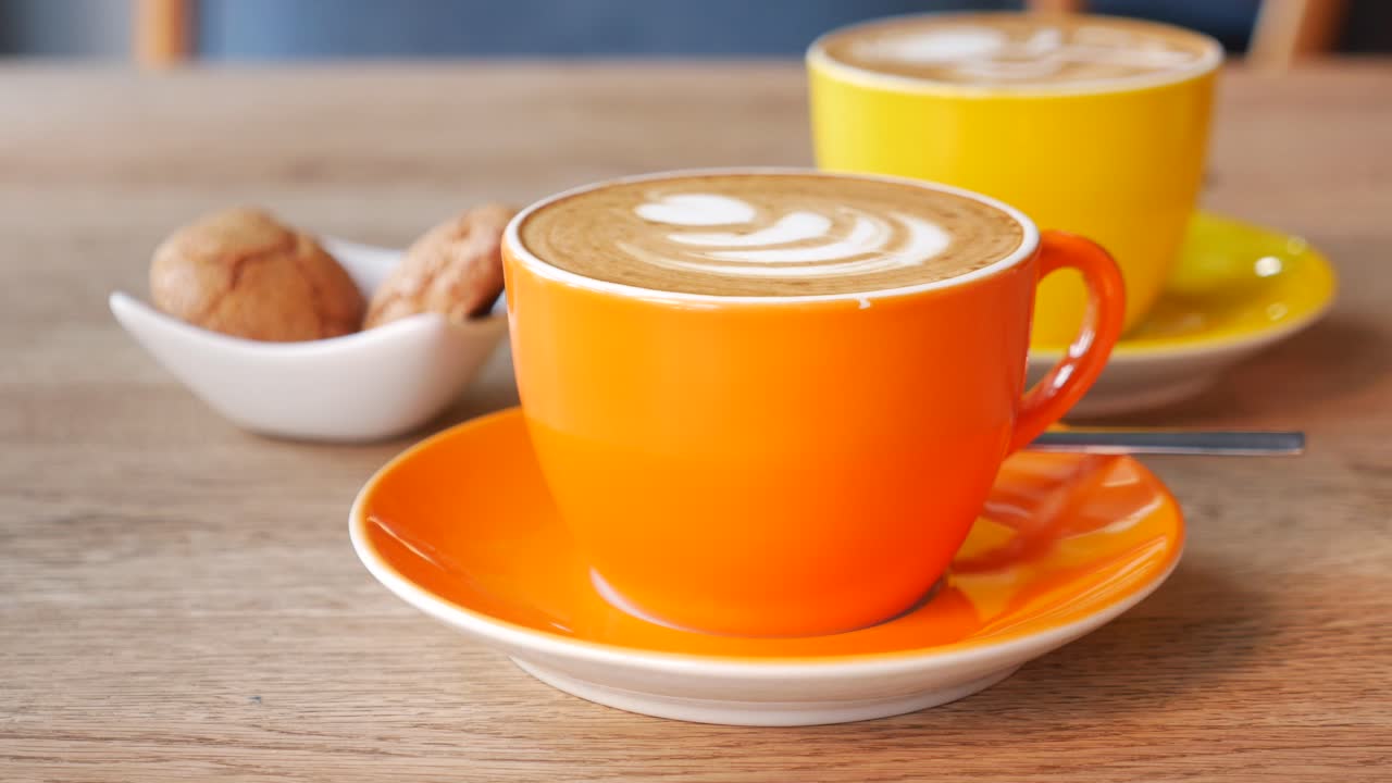 오렌지색과 노란색 커피 컵과 라테 아트