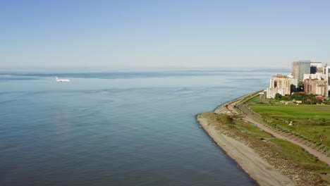 Passenger aircraft flying low above the sea and crossing coastline for landing at Batumi domestic airport