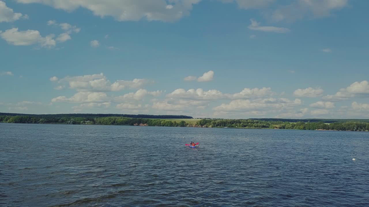 two men are rowing oars through the waves in the river in a kayak to the bank. Active weekend. Wonderful landscape