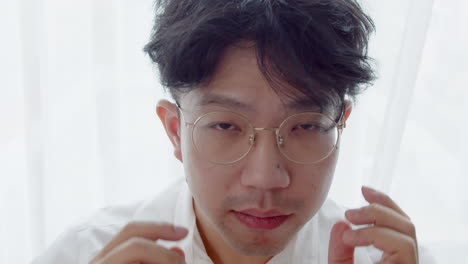 asian man with glasses and healthy good hair looking to the camera and spoiled himself by tidying his hair