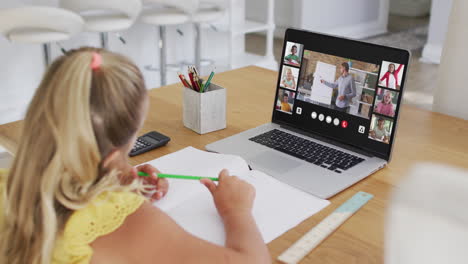 caucasian girl having a video conference with teacher and classmates on laptop at home