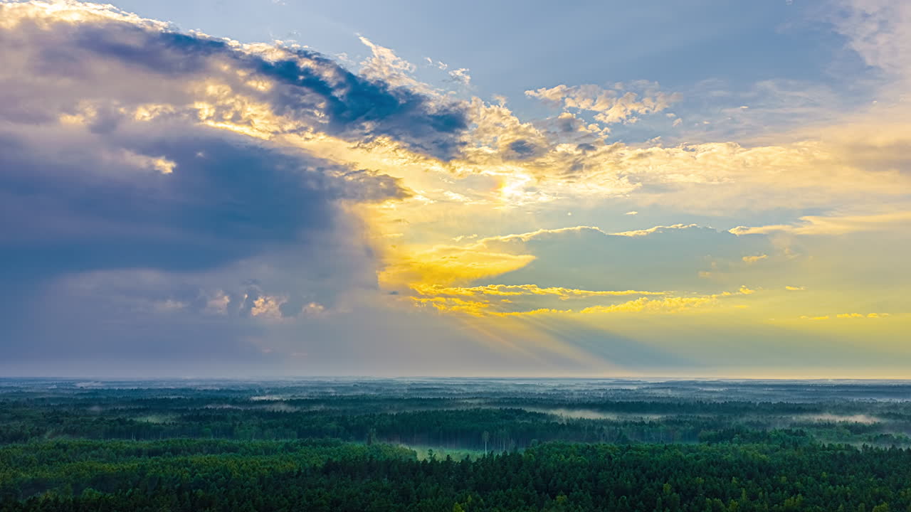 Fast cloud movement over lush green forests at golden hour
