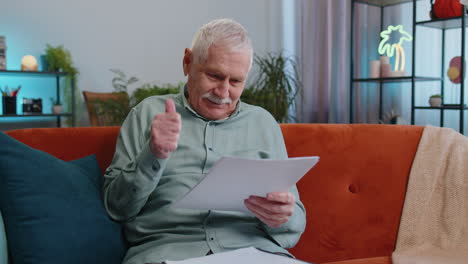 happy senior old man work with documents from home, analyzing information prepare financial report