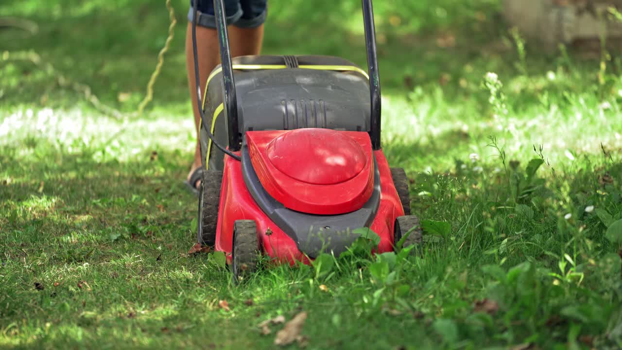 Lawn mower cutting grass. Gardener cutting grass with lawn mower on the beautiful spacious backyard