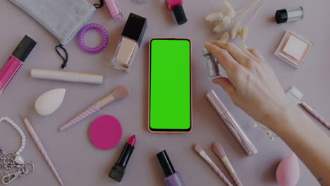 flat lay of makeup products and mobile phone with green screen