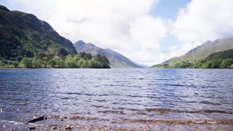 cinematic timelapse of scottish highland lake with clouds and mountains in background