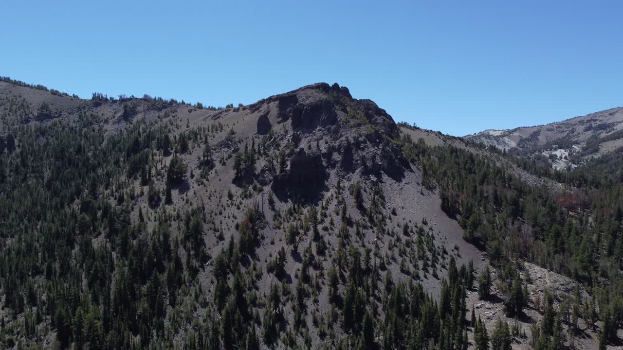 toma aérea de un antiguo pico volcánico que se eleva sobre los árboles y el valle debajo