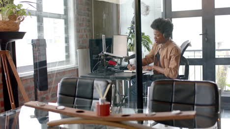 Happy-african-american-man-in-headphones-making-live-podcast-from-home,-copy-space,-slow-motion