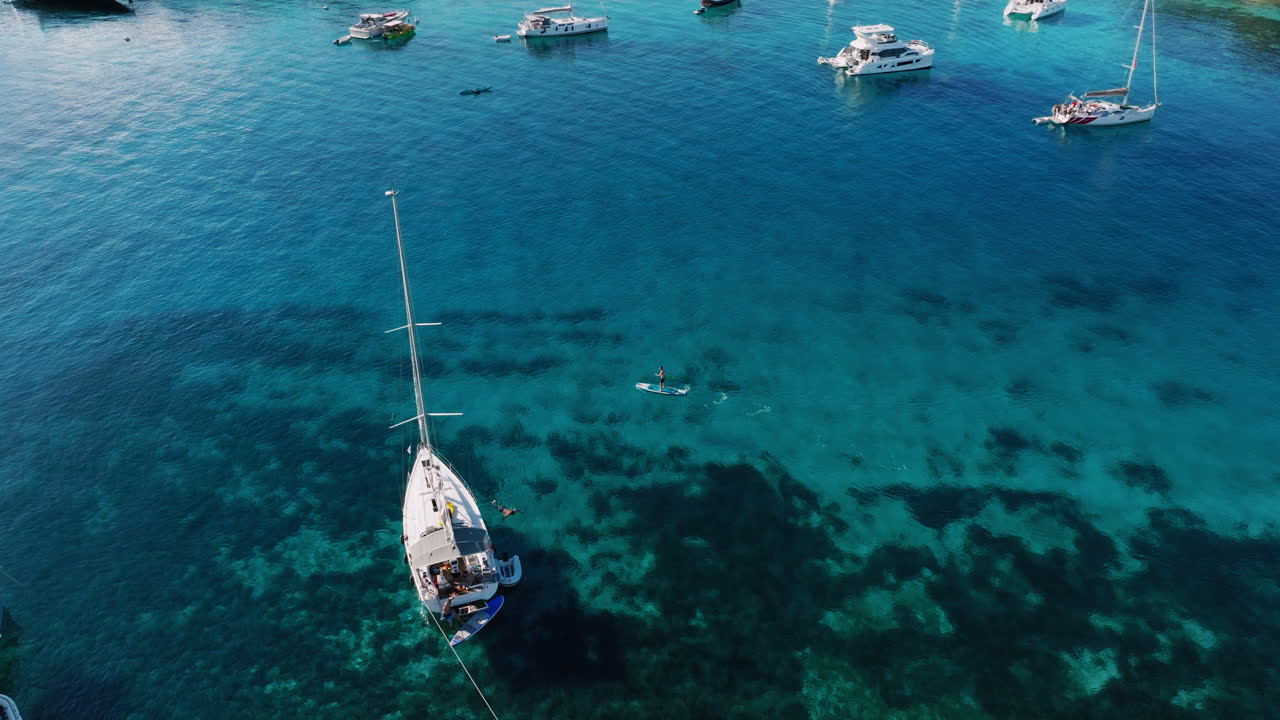 Luxury Yachts and Stand Up Paddleboarders in a Tropical Bay
