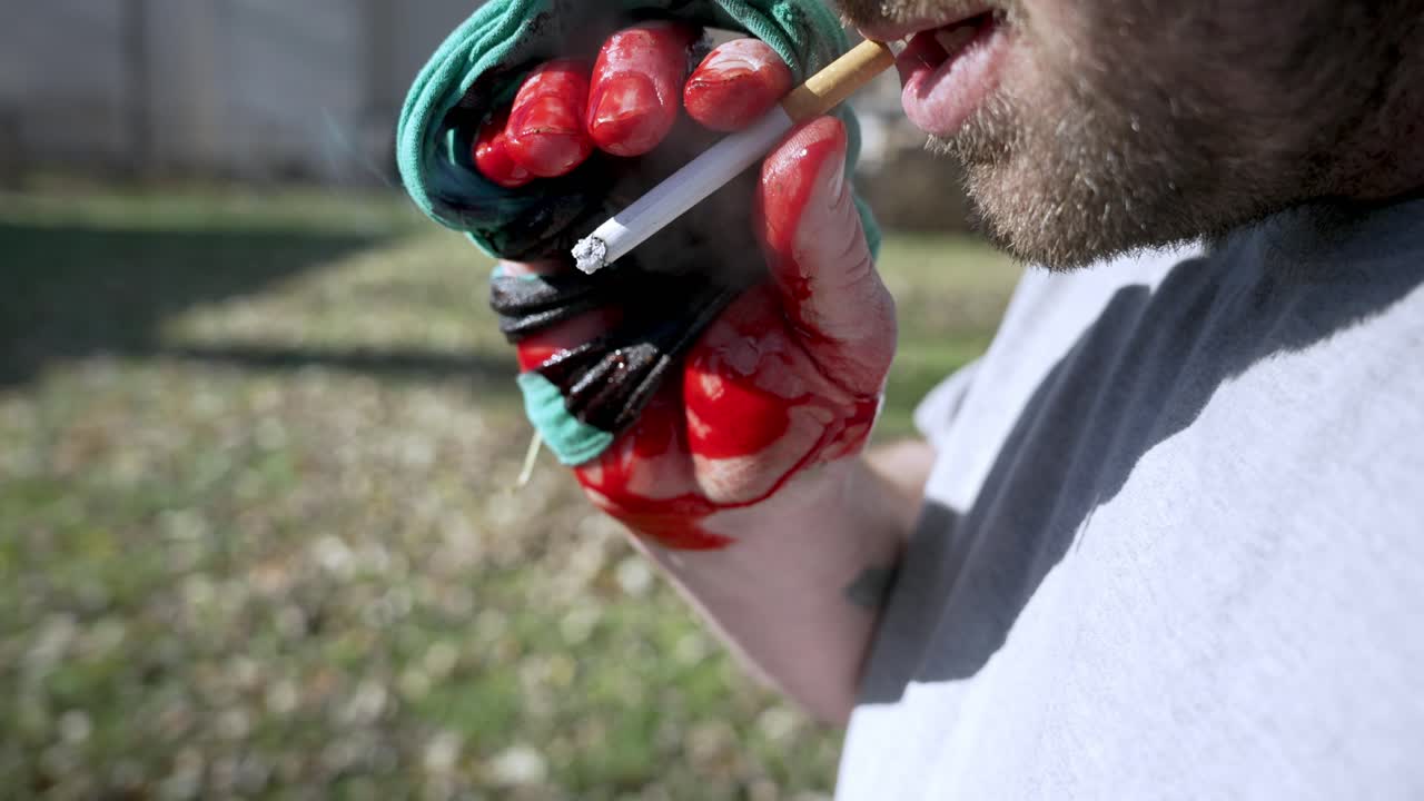 hombre con la mano lesionada fumando un cigarrillo y soplando humo, cámara lenta de primer plano