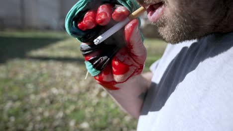 Hombre-Con-La-Mano-Lesionada-Fumando-Un-Cigarrillo-Y-Soplando-Humo,-Cámara-Lenta-De-Primer-Plano