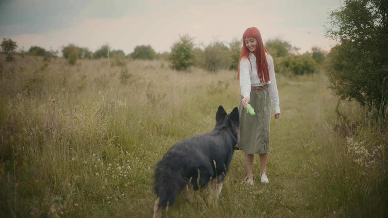 A woman playing with her dog in a field