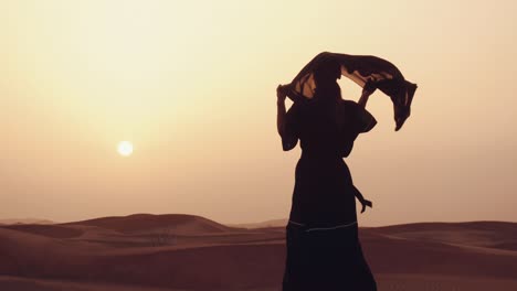 mujer musulmana de pie cerca de la mezquita en el desierto. viento fuerte oriente medio paz sin guerra