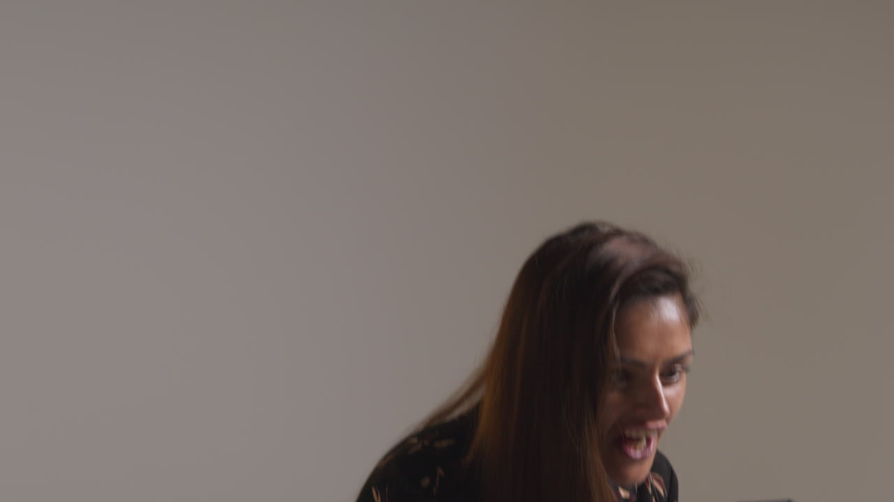 Studio Shot Of Excited Woman With Mobile Phone Celebrating Winning Money Against Grey Background