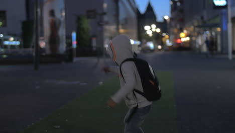 Niño-Divirtiéndose-Y-Engañando-En-La-Calle-Por-La-Noche.