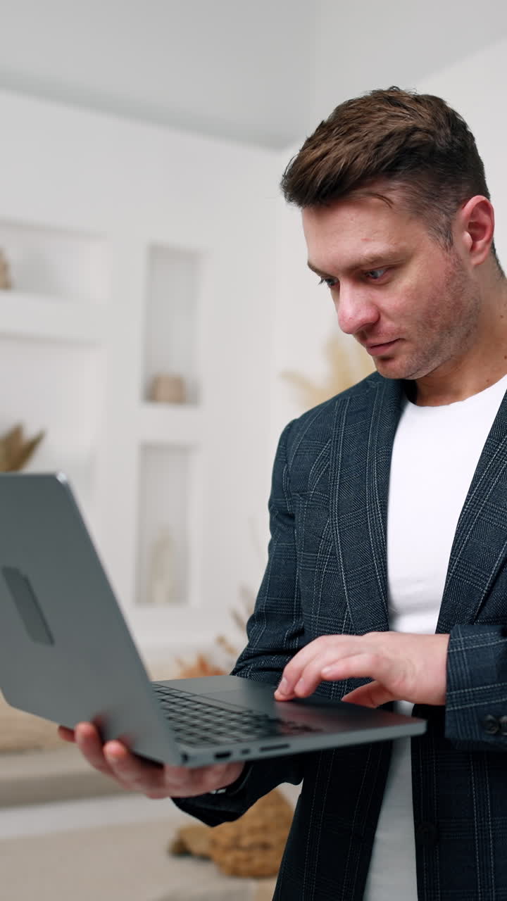 Caucasian male in jacket holding a laptop. Male entrepreneur stands in the room