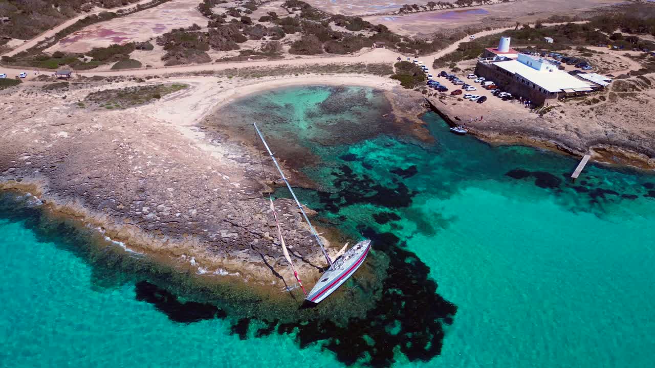 shit happen Sailboat stranded on cliff near the coast of Formentera Island, Spain, during a summer sunny day. Unique aerial view flight tilt down drone