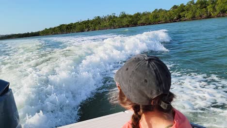 woman pointing finger while searching and sitting in back of boat staring at the ocean waves as they drive through the backwater shallow bays in the gulf of mexico off the coast of louisiana