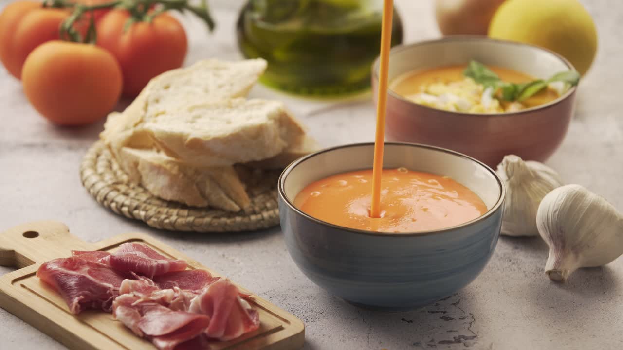 Serving salmorejo in a bowl, with various ingredients around. Salmorejo is a typical Andalusian dish, similar to gazpacho