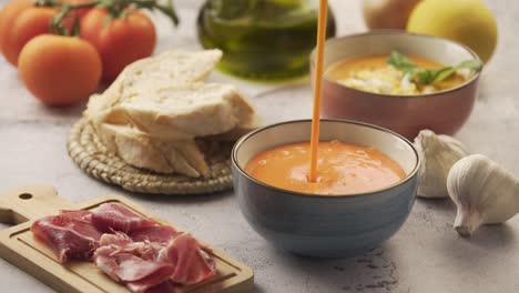 serving salmorejo in a bowl, with various ingredients around. salmorejo is a typical andalusian dish, similar to gazpacho