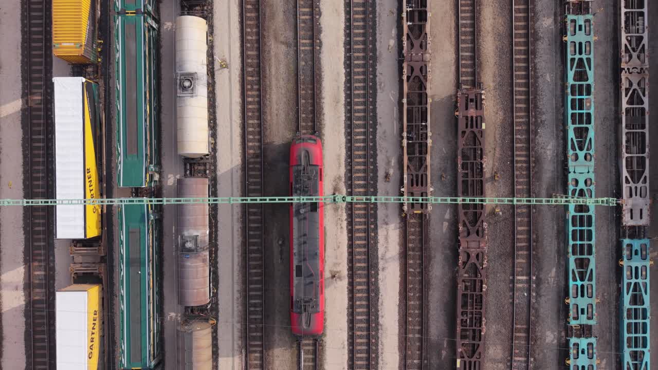 Vista aerea dall'alto di più treni merci fermi su binari ferroviari paralleli in un deposito ferroviario industriale mentre un drone sorvola l'area