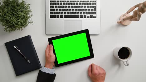 las manos de un hombre sosteniendo una tableta digital con una pantalla verde