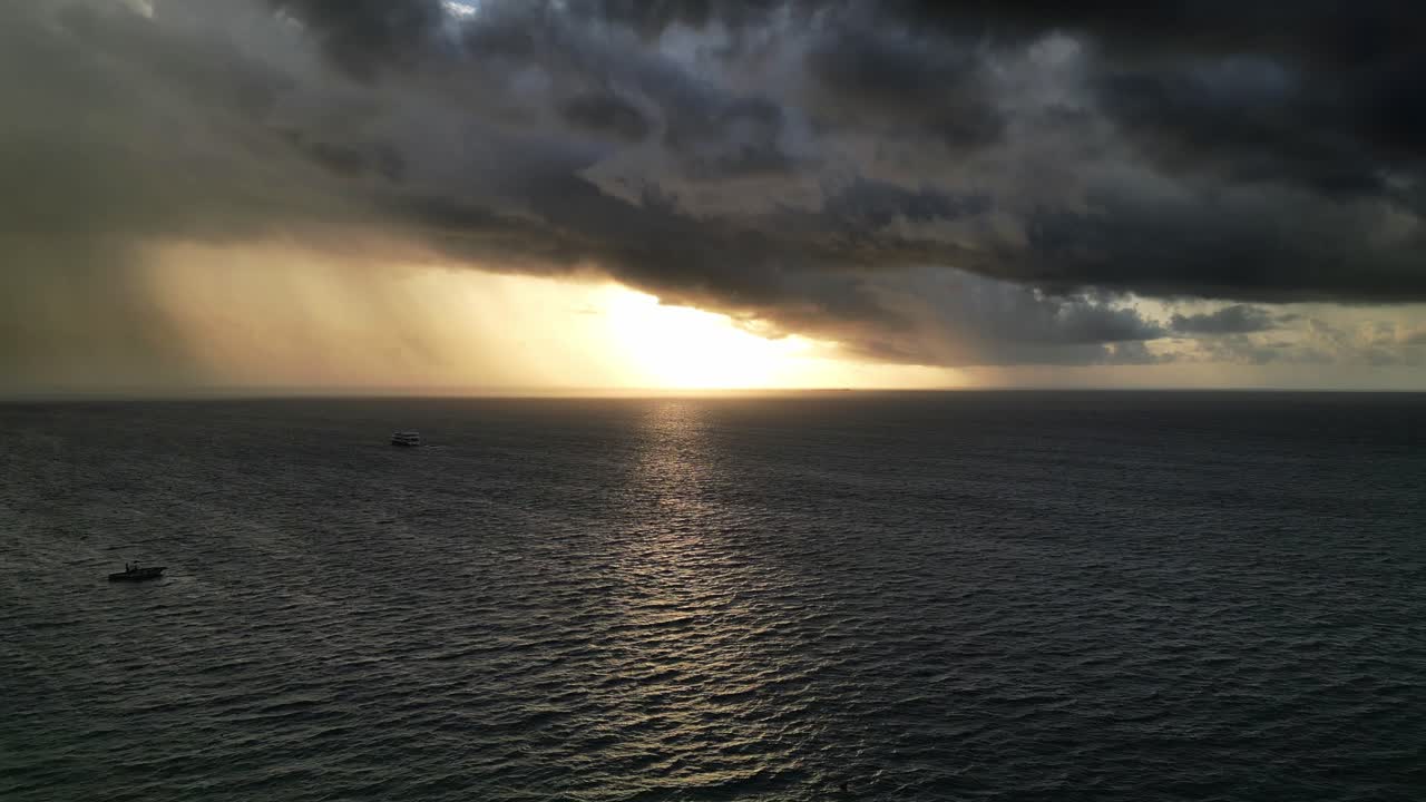un ferry navegando al atardecer en un mar tranquilo con una tormenta inminente en el horizonte, aérea