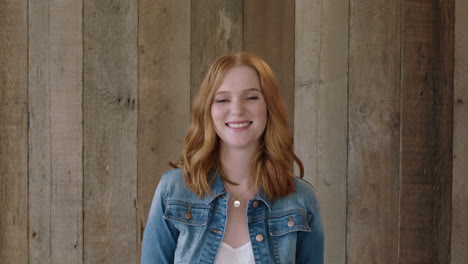 young-stylish-red-head-woman-portrait-of-beautiful-girl-smiling-happy-at-camera-wearing-denim-jacket-wooden-background