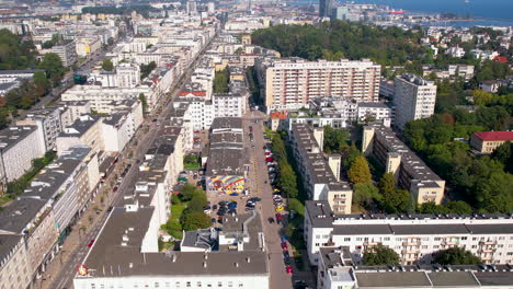 Aerial-dolly-tilt-up-reveals-modern-coastal-city-of-Gdynia-with-white-apartment-buildings-lining-the-road