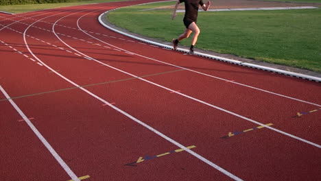 male runner running on red race track - slow motion