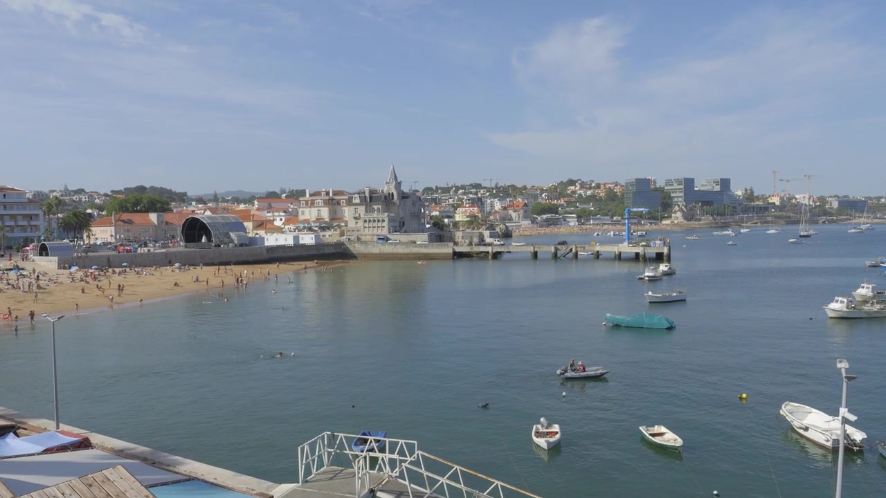 Barche da pesca nella Baia di Cascais ancorate al largo di Praia da Ribeira con lo skyline della città, Portogallo
