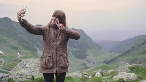 a young woman hiker climbs mountains and does selfie on smartphone camera. transfagarasan, carpathian mountains in romania