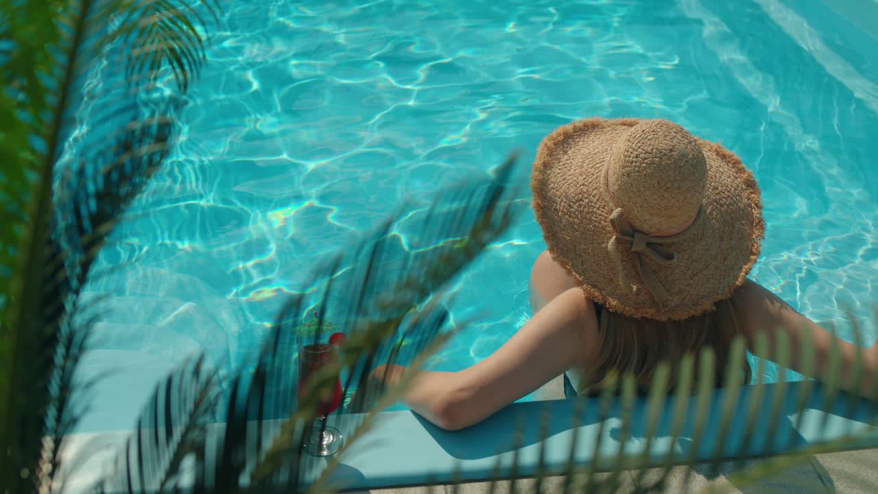 Frau entspannt sich am Pool mit einem Cocktail