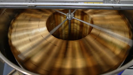 wooden frames with organic honey being rotated quickly in the centrifuge machine. apiarist gathering honey harvest on his farm.
