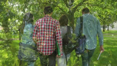 composite video of close up of leaves against rear view of group of people walking in the garden