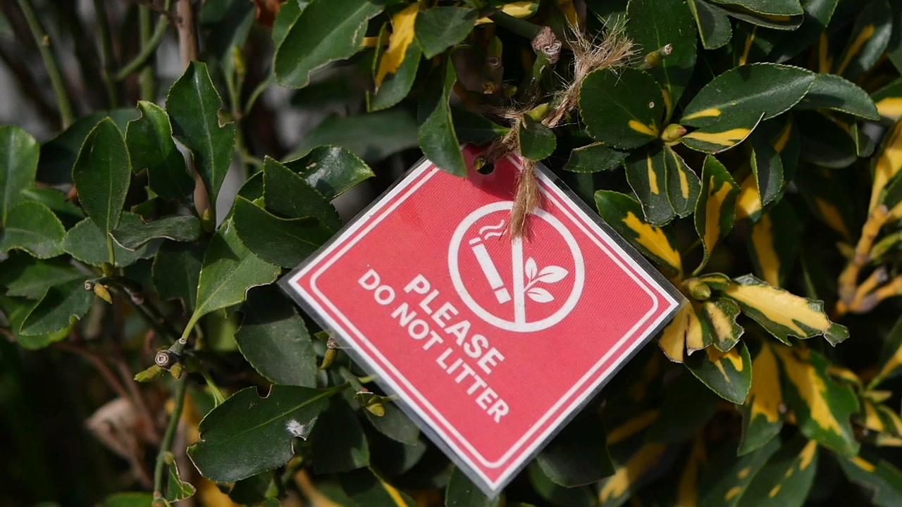 Red 'Please Do Not Litter' Sign Hanging on a Bush