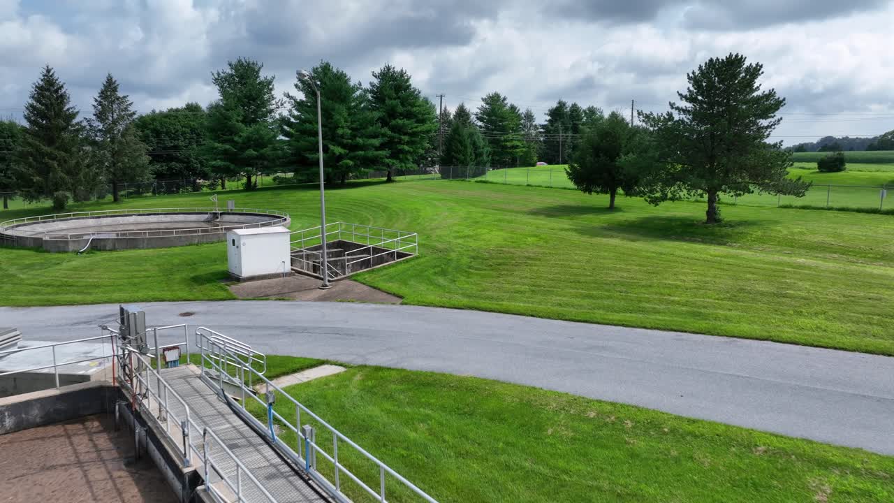Industrial American sewage treatment plant in Lititz, Pennsylvania. Aerial tilt up shot. Green grass in suburb district of town. Brown water in pools