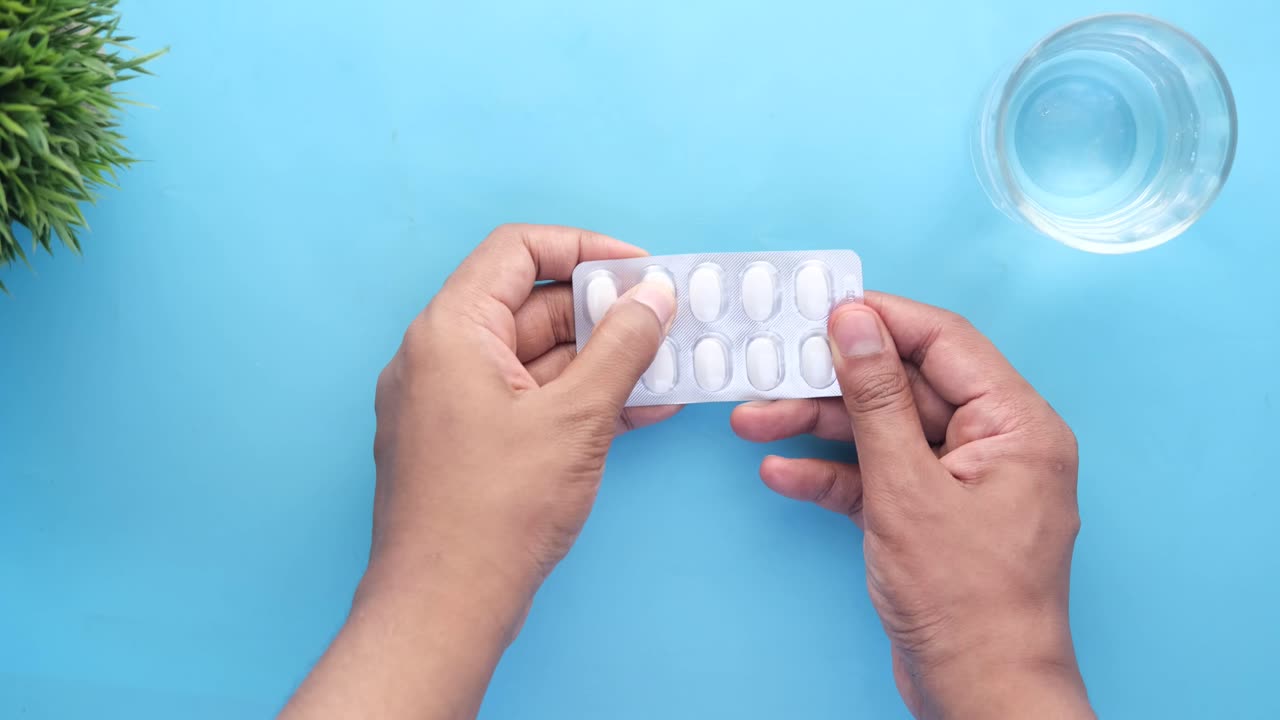 알약과 물 한 잔을 들고 있는 사람