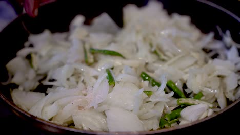 stirring fresh sliced white onions in saucepan with