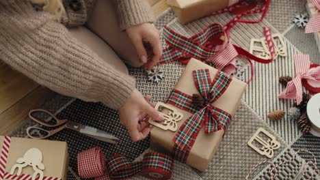 vista superior de una mujer caucásica irreconocible envolviendo regalos de navidad en el suelo.