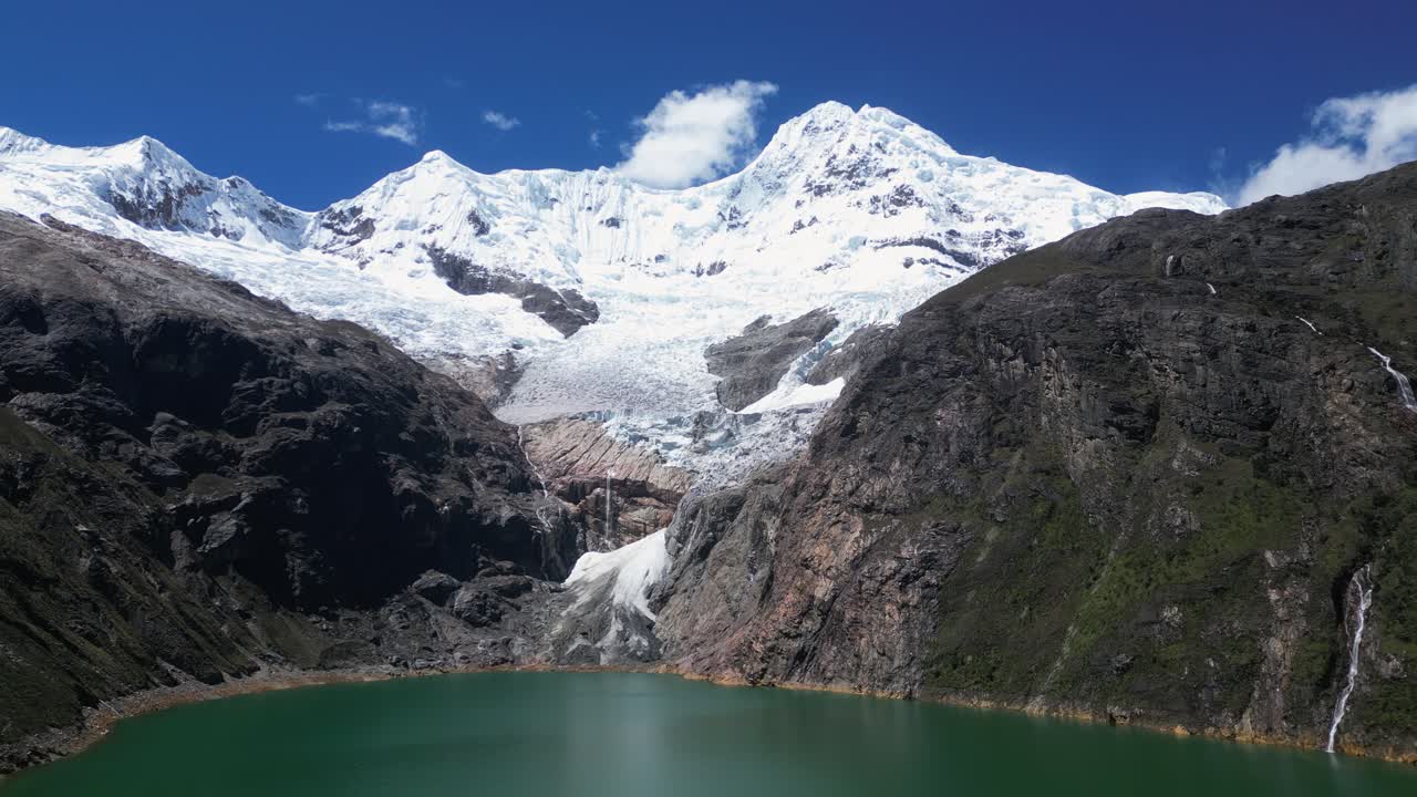 Aerial: Steep rock cliffs surround Rajucolta lake in Peru Cordillera
