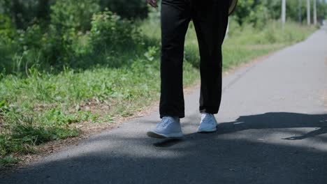 young man walking with guitar on street near forest