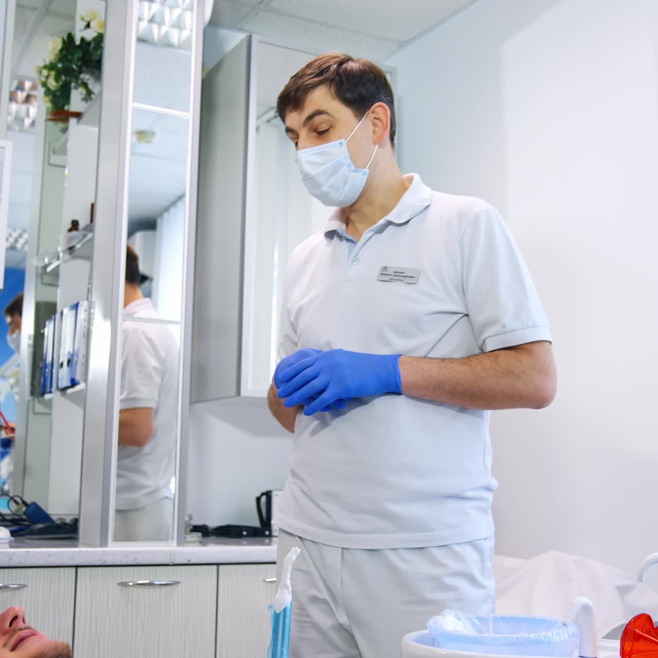 Alunos do departamento de odontologia usando máscaras ouvem o professor. Aluna sentada atendendo o paciente