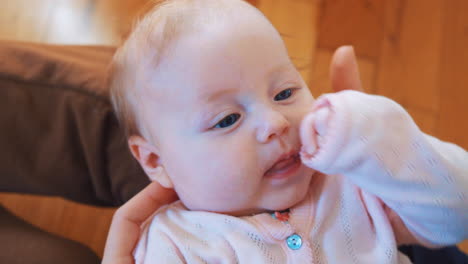 a little baby who paws his hands and looks at his mother