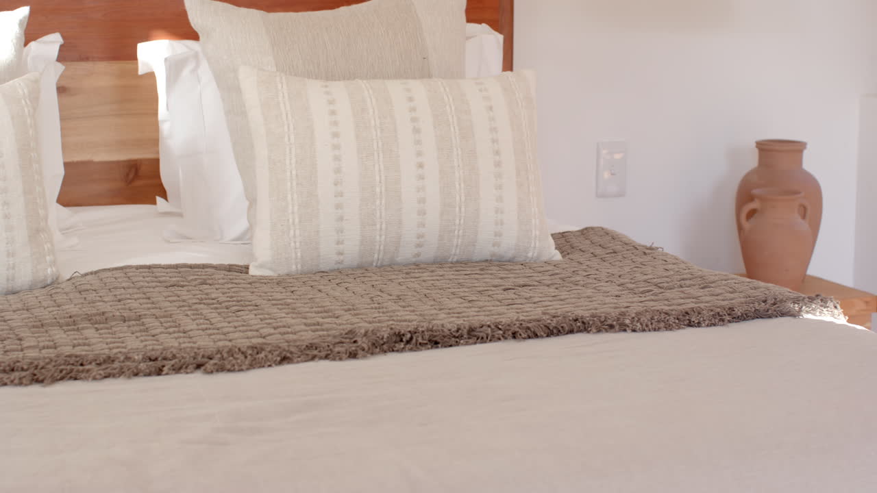 Cozy bedroom with neatly arranged pillows and textured blanket on bed, at home