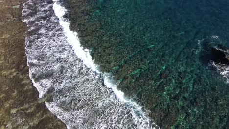 volando sobre la costa con olas rompiendo en arrecifes de piedra de forma única